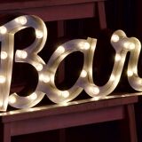 Enseigne lumineuse en lettrage aluminium formant le mot "bar"