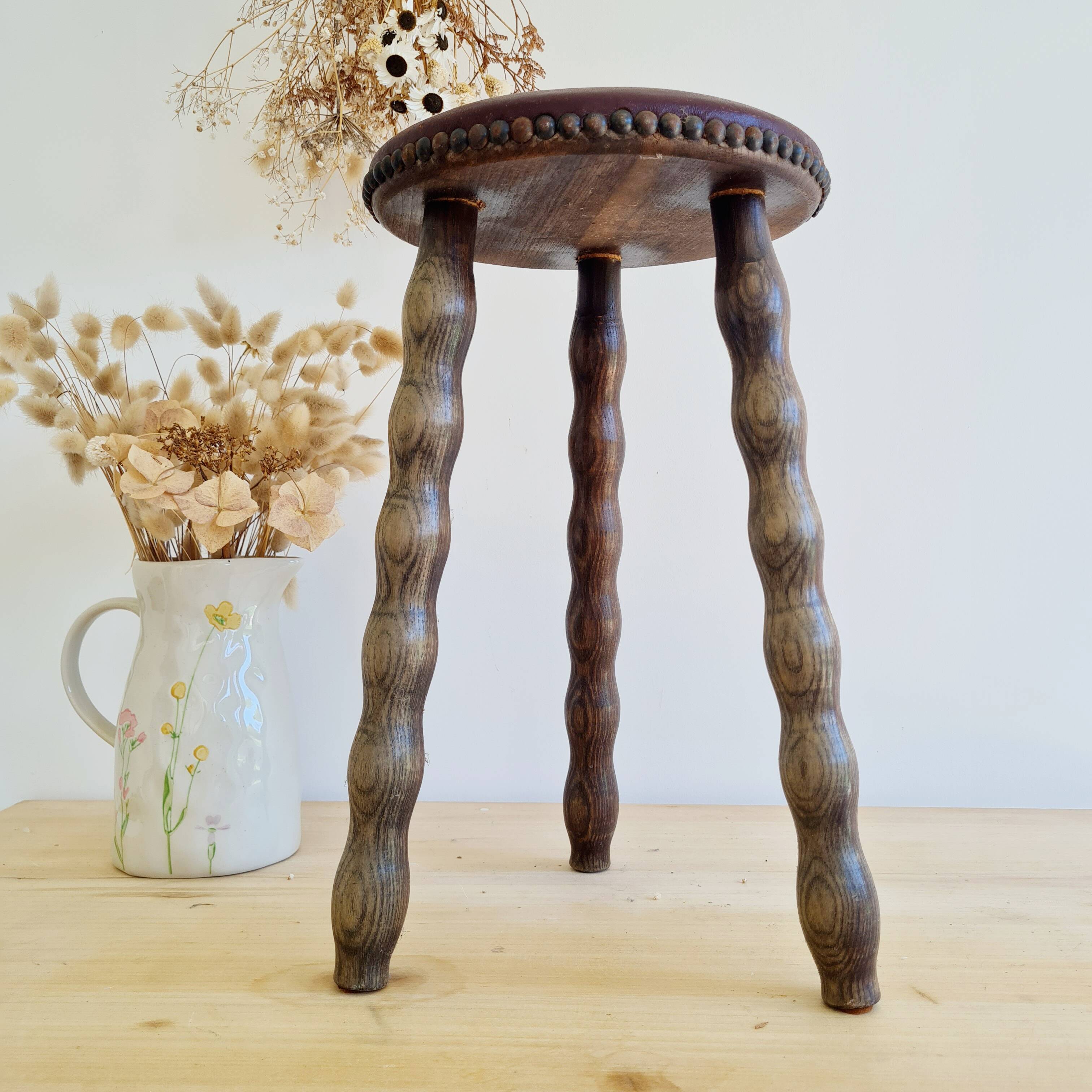 Antique tripod stool with turned wooden legs and leather seat.