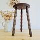 Antique tripod stool with turned wooden legs and leather seat.