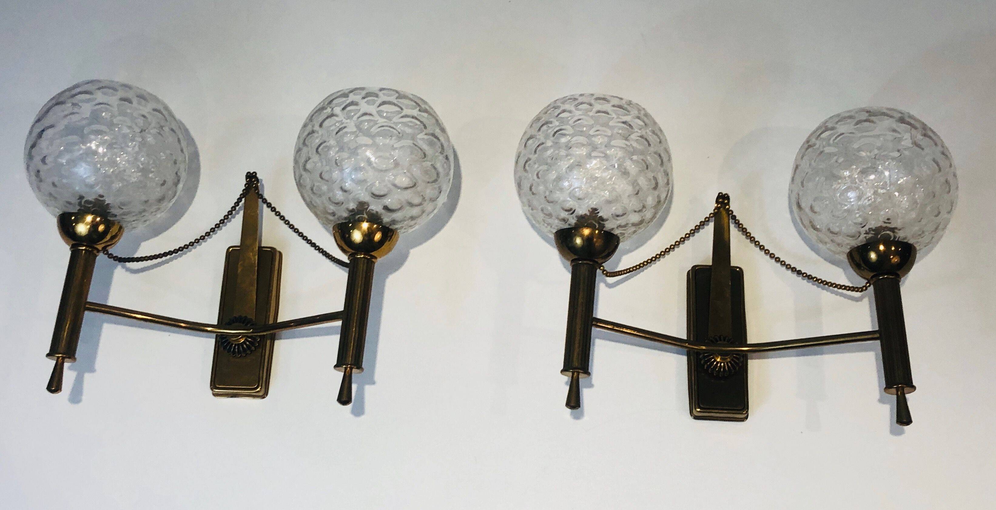 Pair of brass wall lights with glass globes. Around 1970.