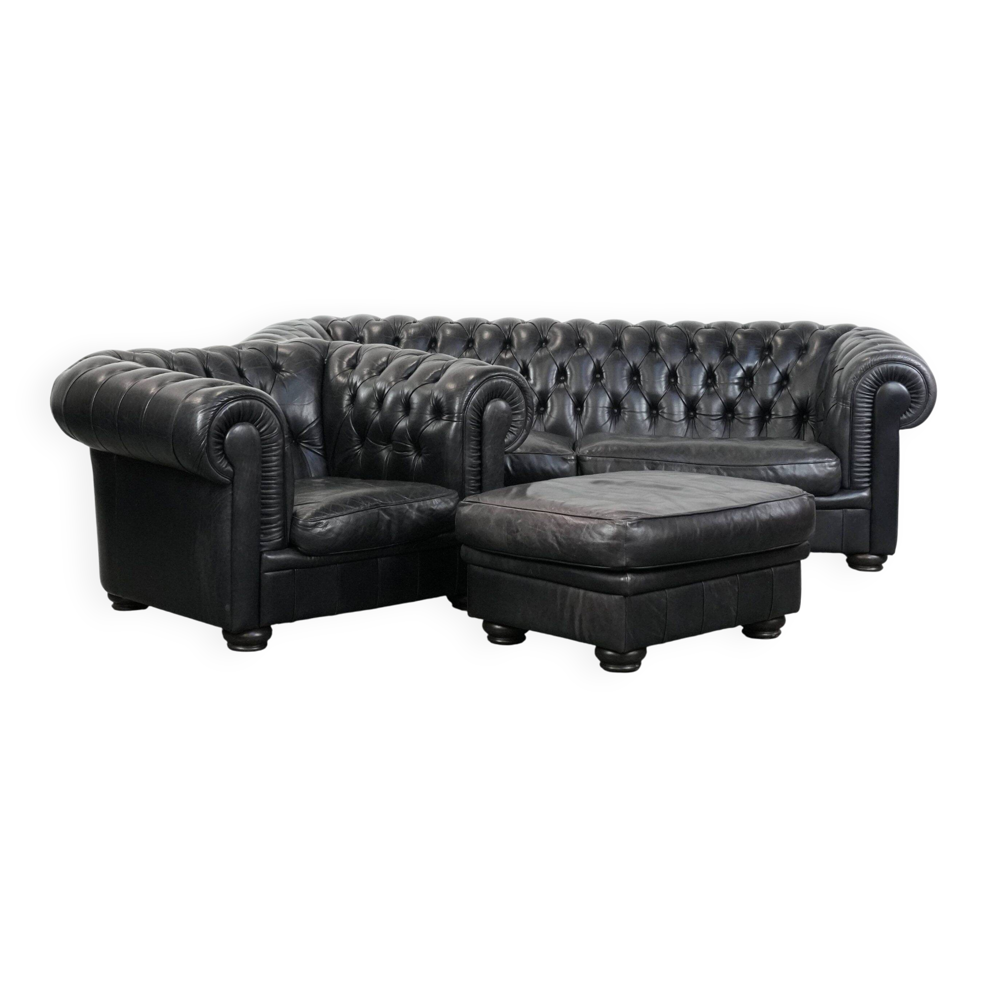 Ensemble composé d'un canapé chesterfield noir, d'un fauteuil et d'un pouf.