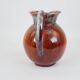 Large red and blue glazed ceramic pitcher signed Delène under the base