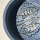 Glazed blue ceramic bowl with stylised fish decoration.