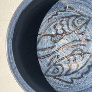 Glazed blue ceramic bowl with stylised fish decoration.