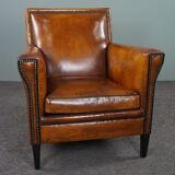 Art deco armchair in sheepskin with black piping and decorative nails