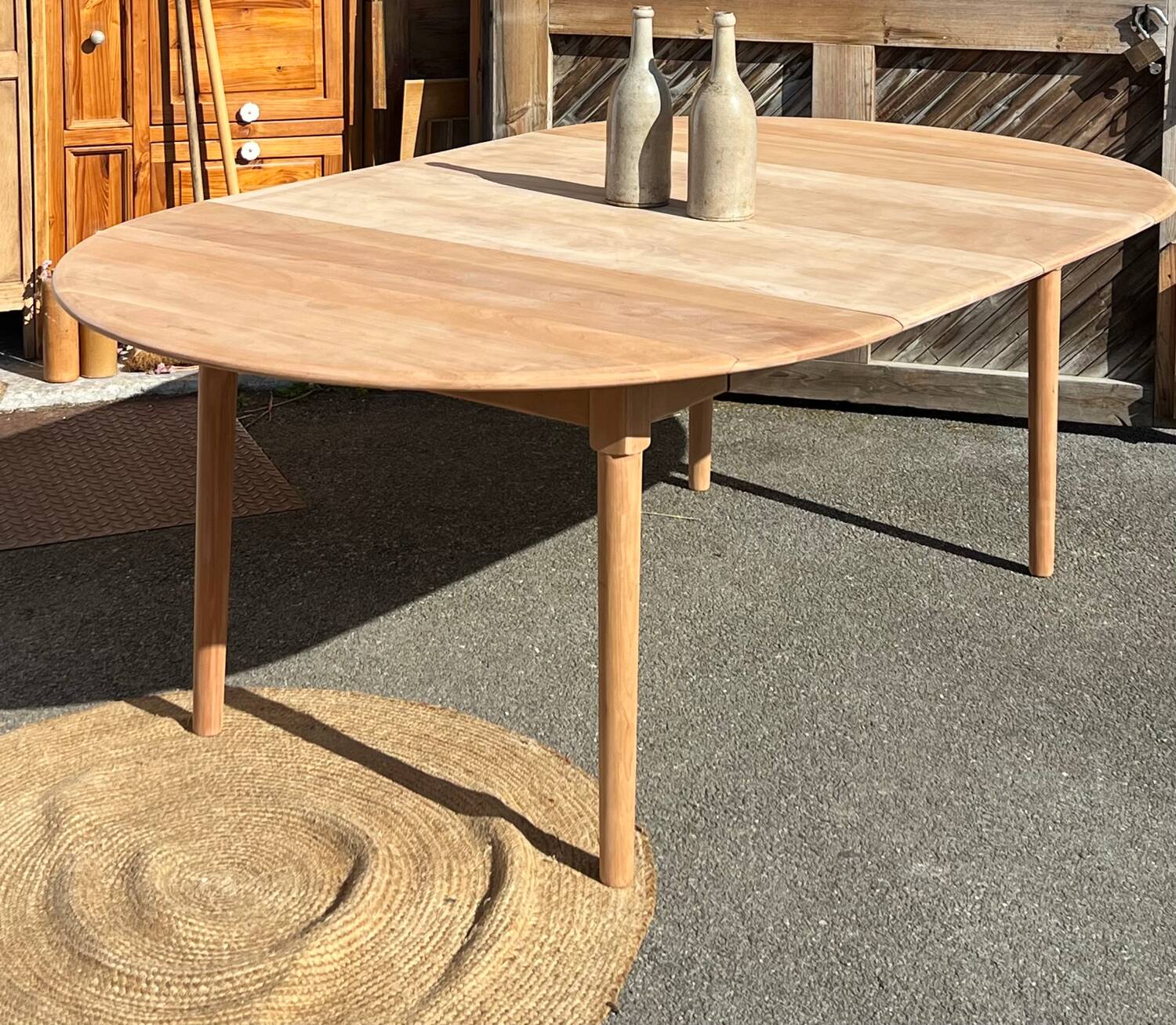 Large round family table with 2 extensions in solid raw wood.