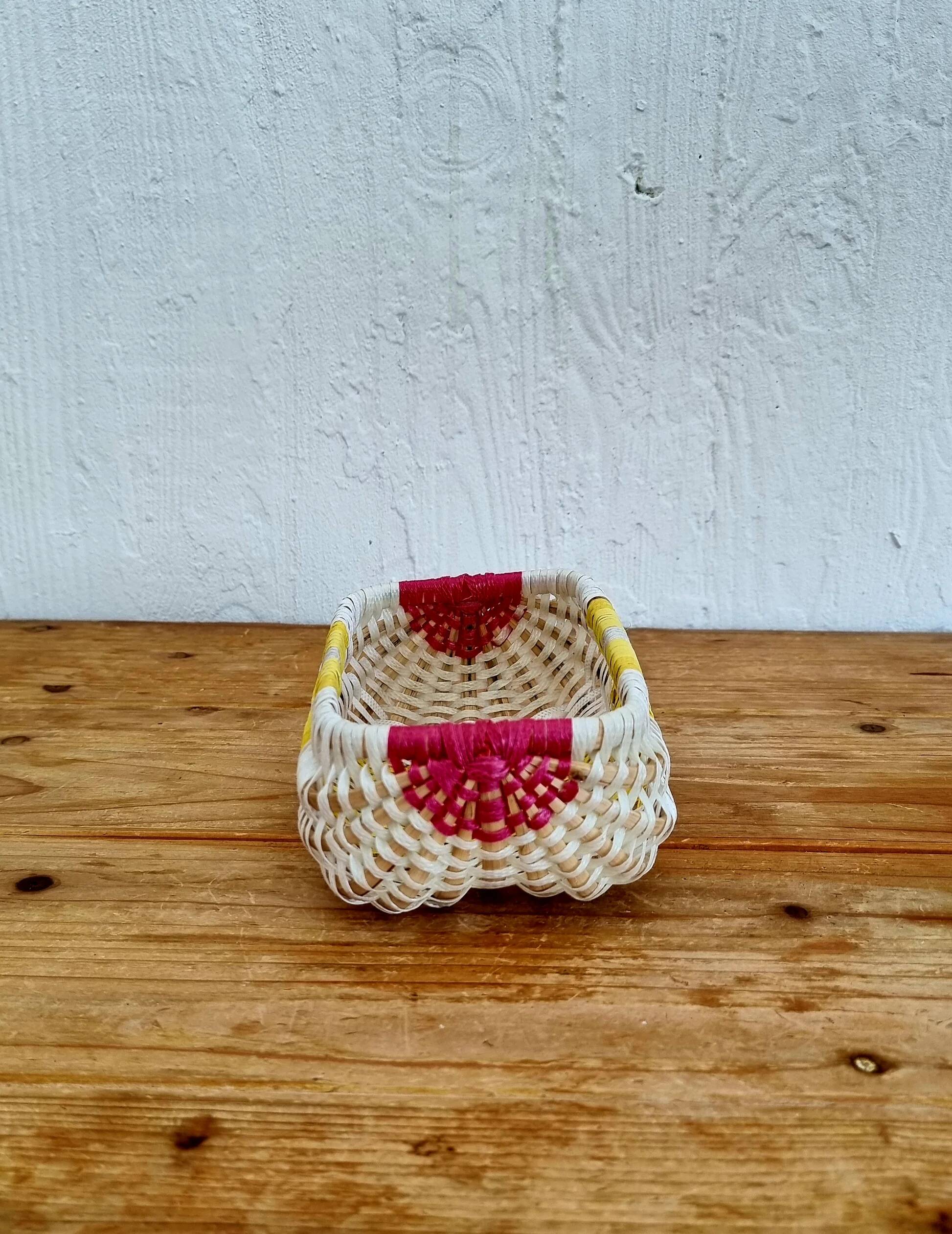 Vintage woven basket in yellow, white, and pink plastic.
