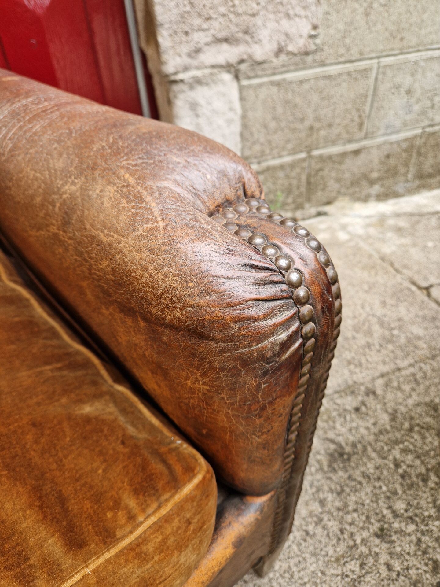 Antique club chair in patinated brown leather, early 20th century English style.