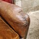Antique club chair in patinated brown leather, early 20th century English style.
