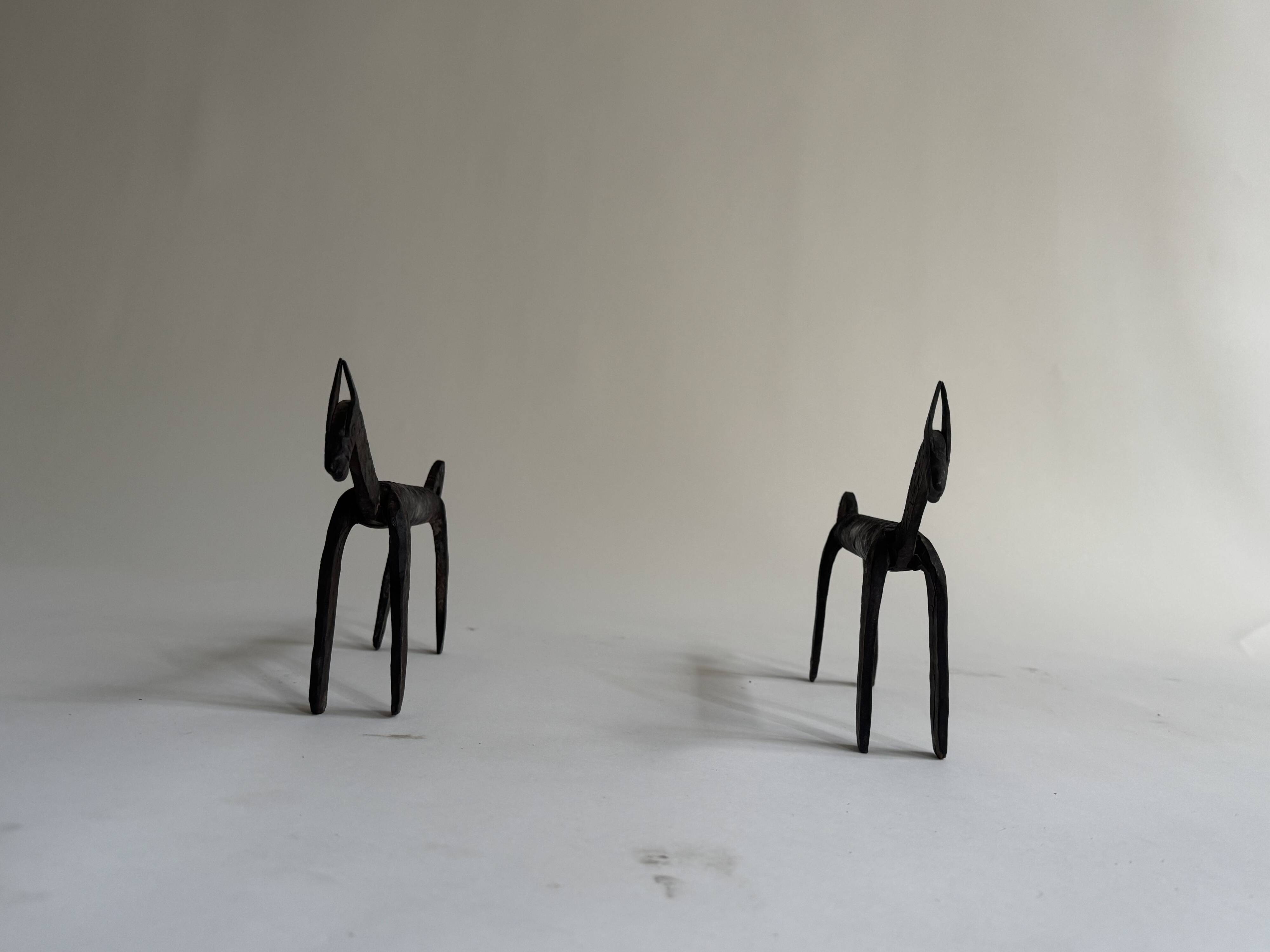 Pair of animal-shaped wrought iron and hammered fire dogs in primitive brutalist style.