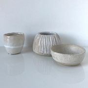 Meeting of three artist's ceramic objects including two pots and a cream covered bowl