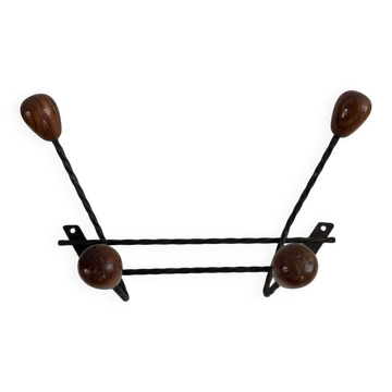 Wall-mounted coat rack in wrought iron with turned wooden knobs.