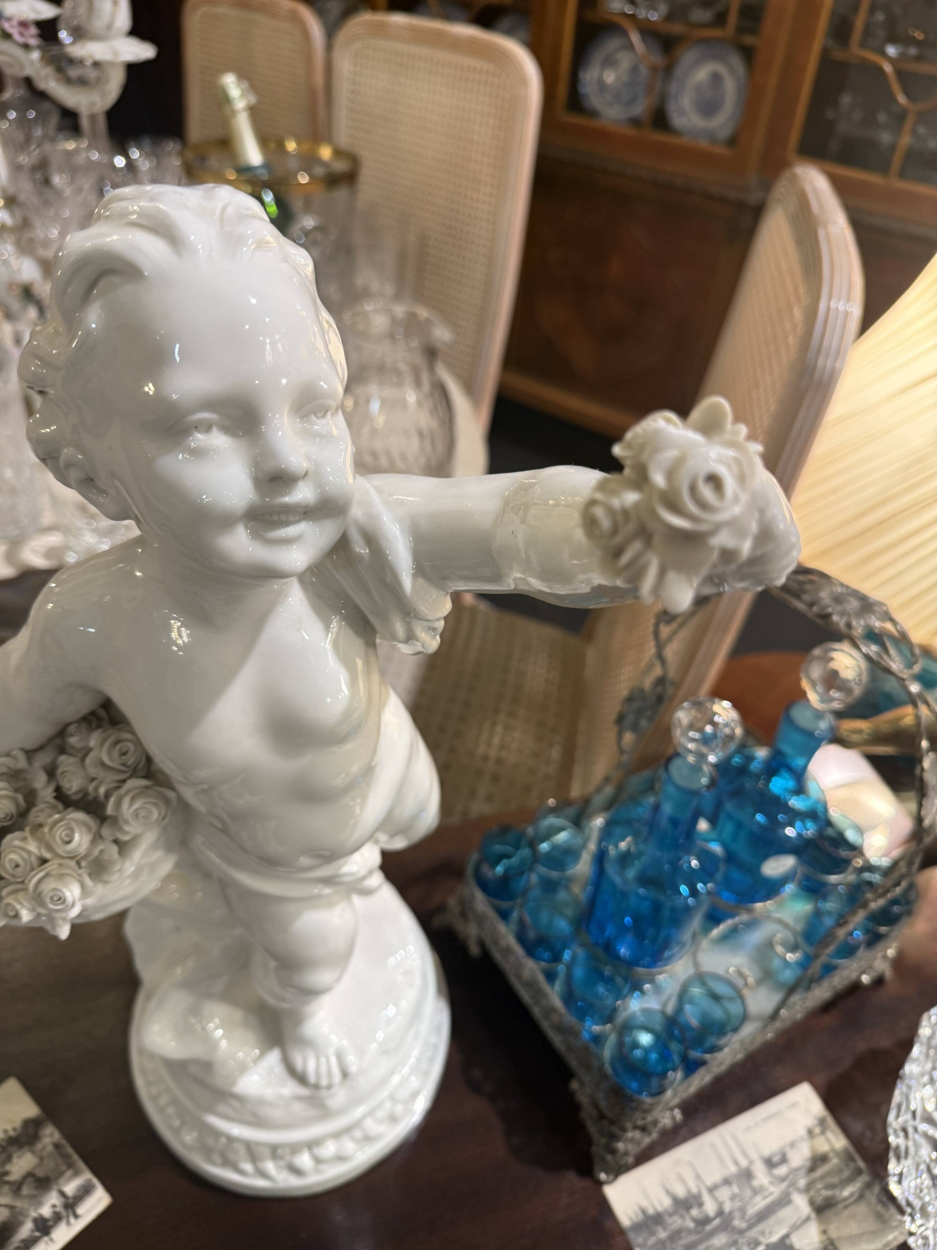 Child statue with flowers in porcelain, signed.