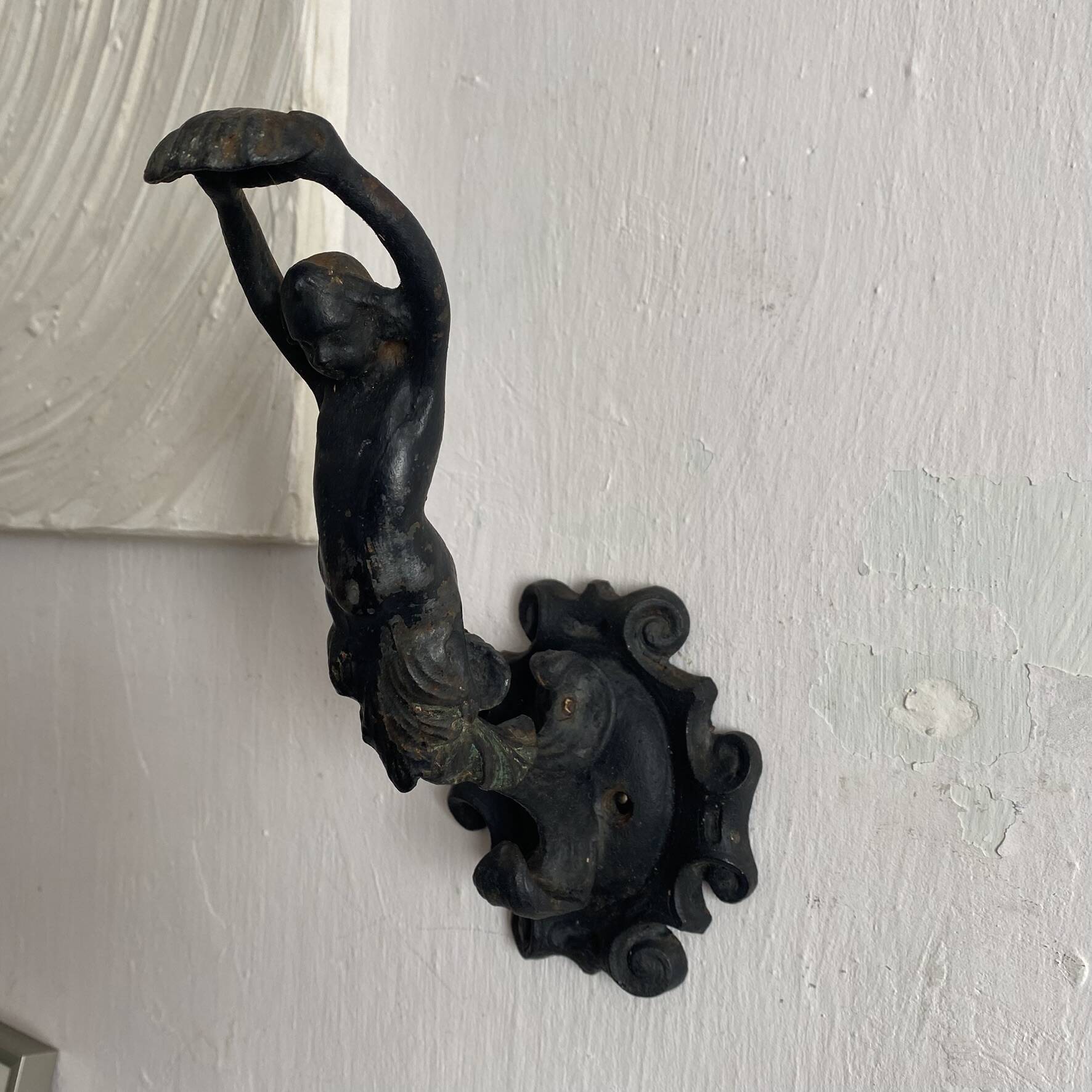 Antique cast iron coat hook with swimmer and shell basin.