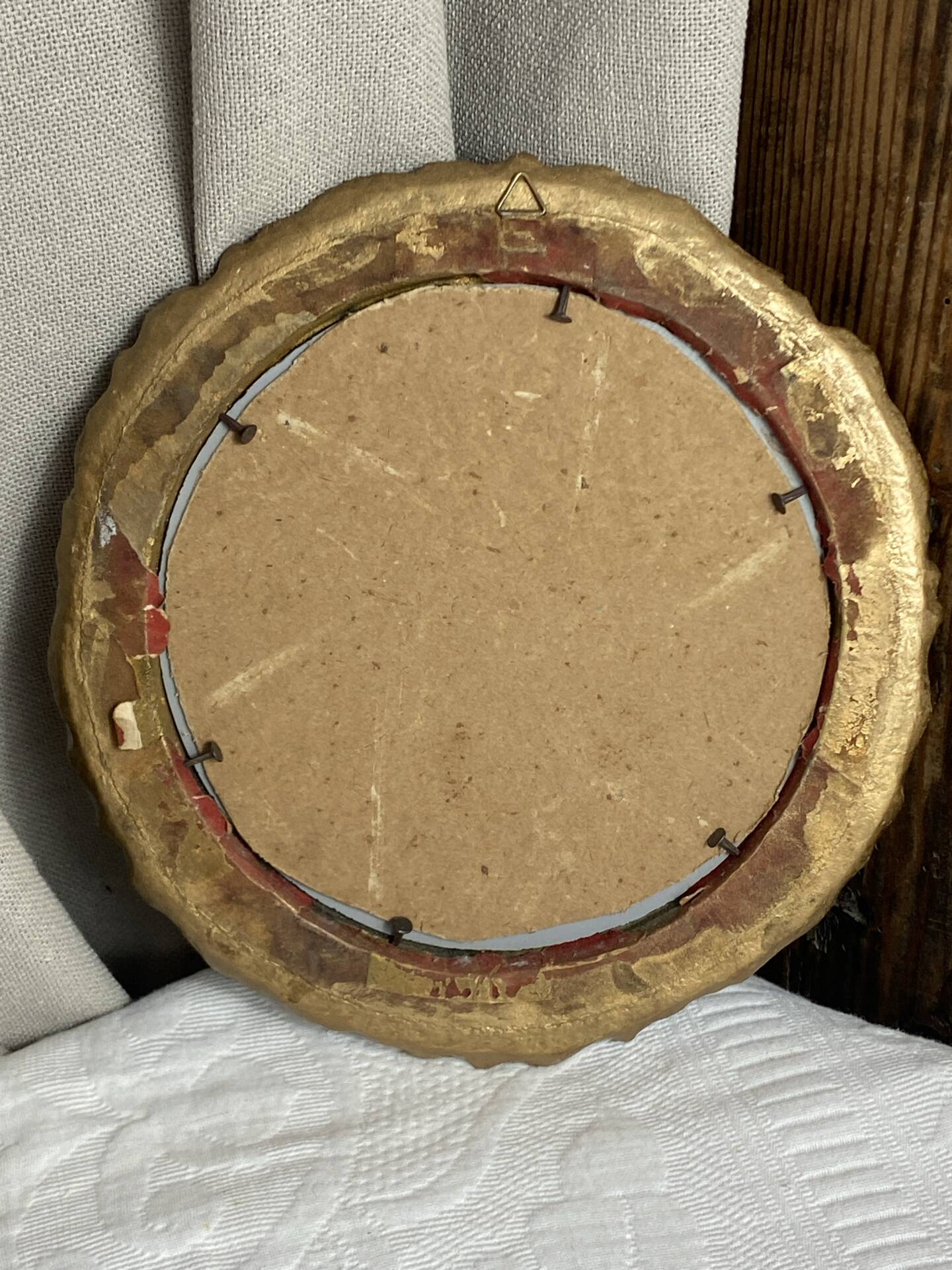 Round wooden mirror in golden colour.