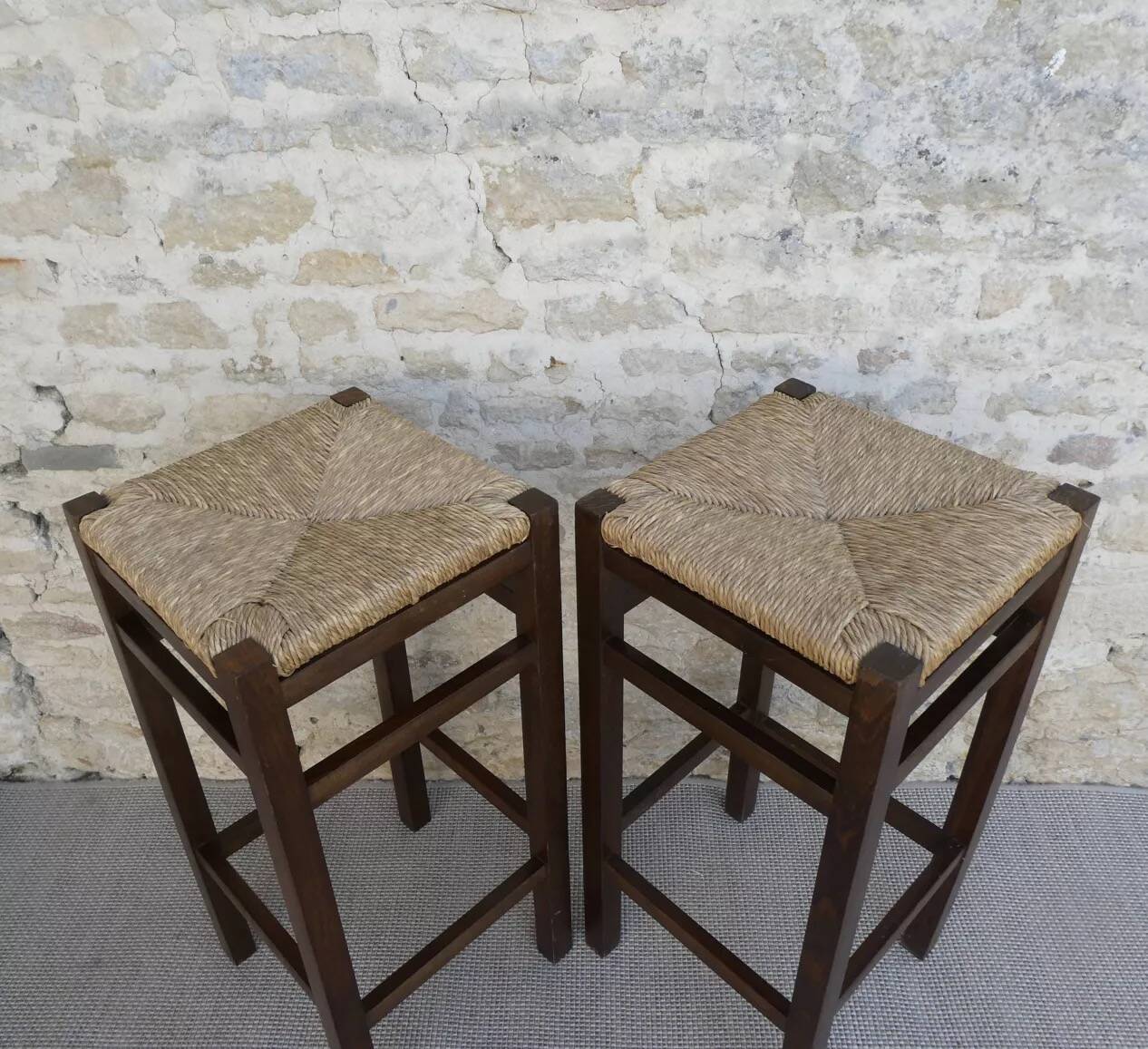 pair of bar stools, made of wood with a straw seat
