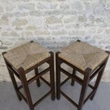 pair of bar stools, made of wood with a straw seat