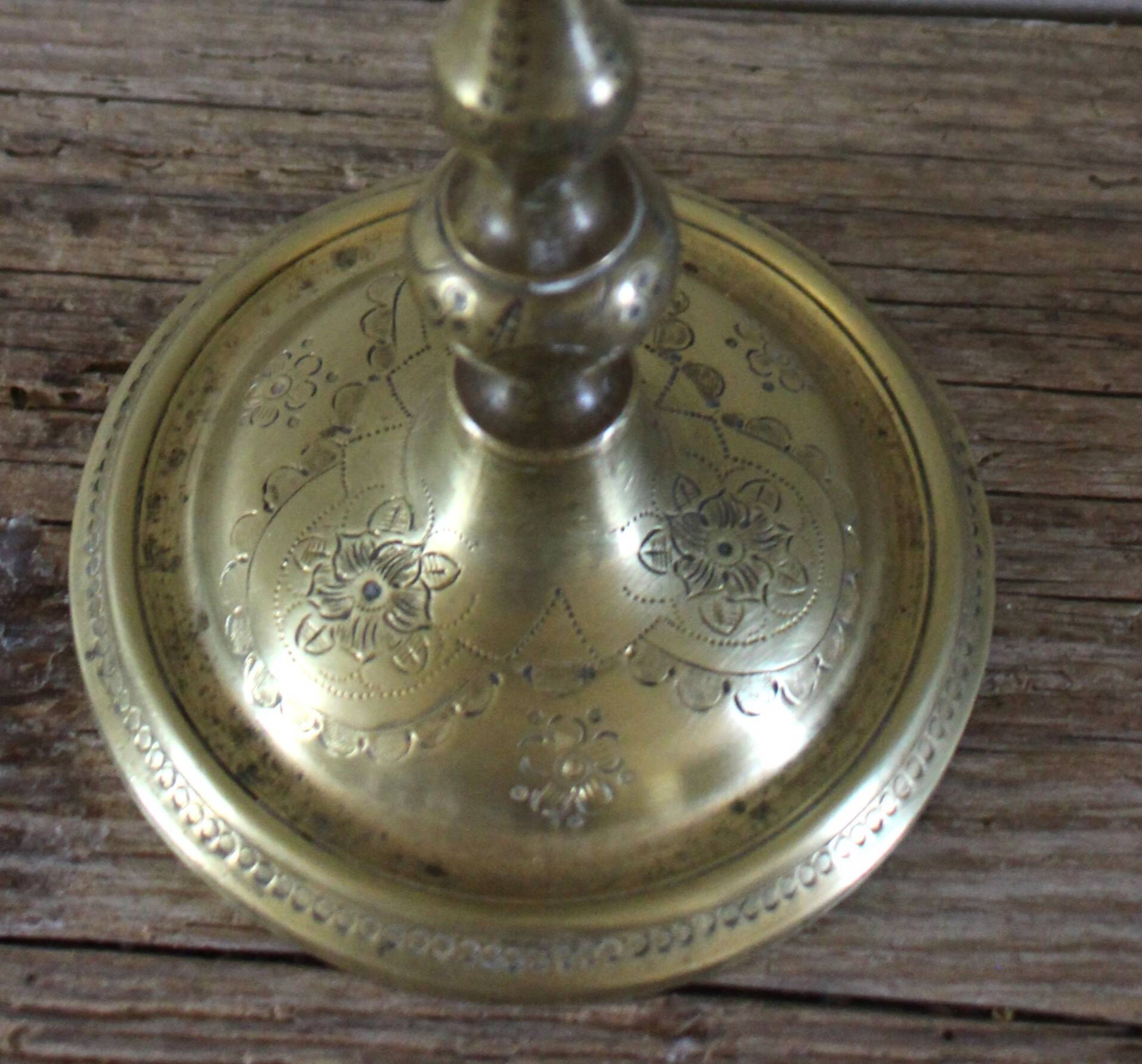 Brass candle holder with flowers and round shape.