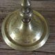 Brass candle holder with flowers and round shape.