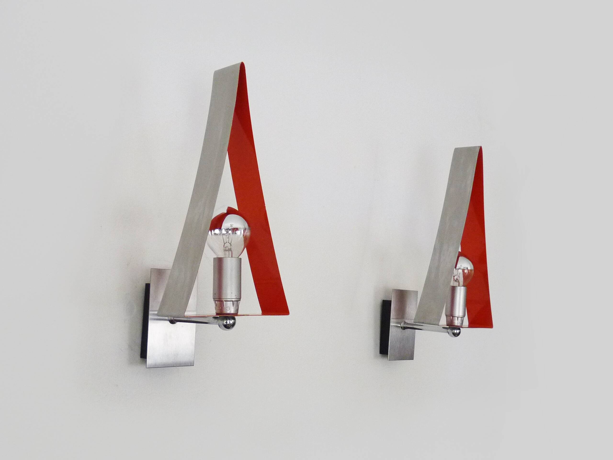 Pair of triangular wall sconces in chrome metal and orange. 1970s.