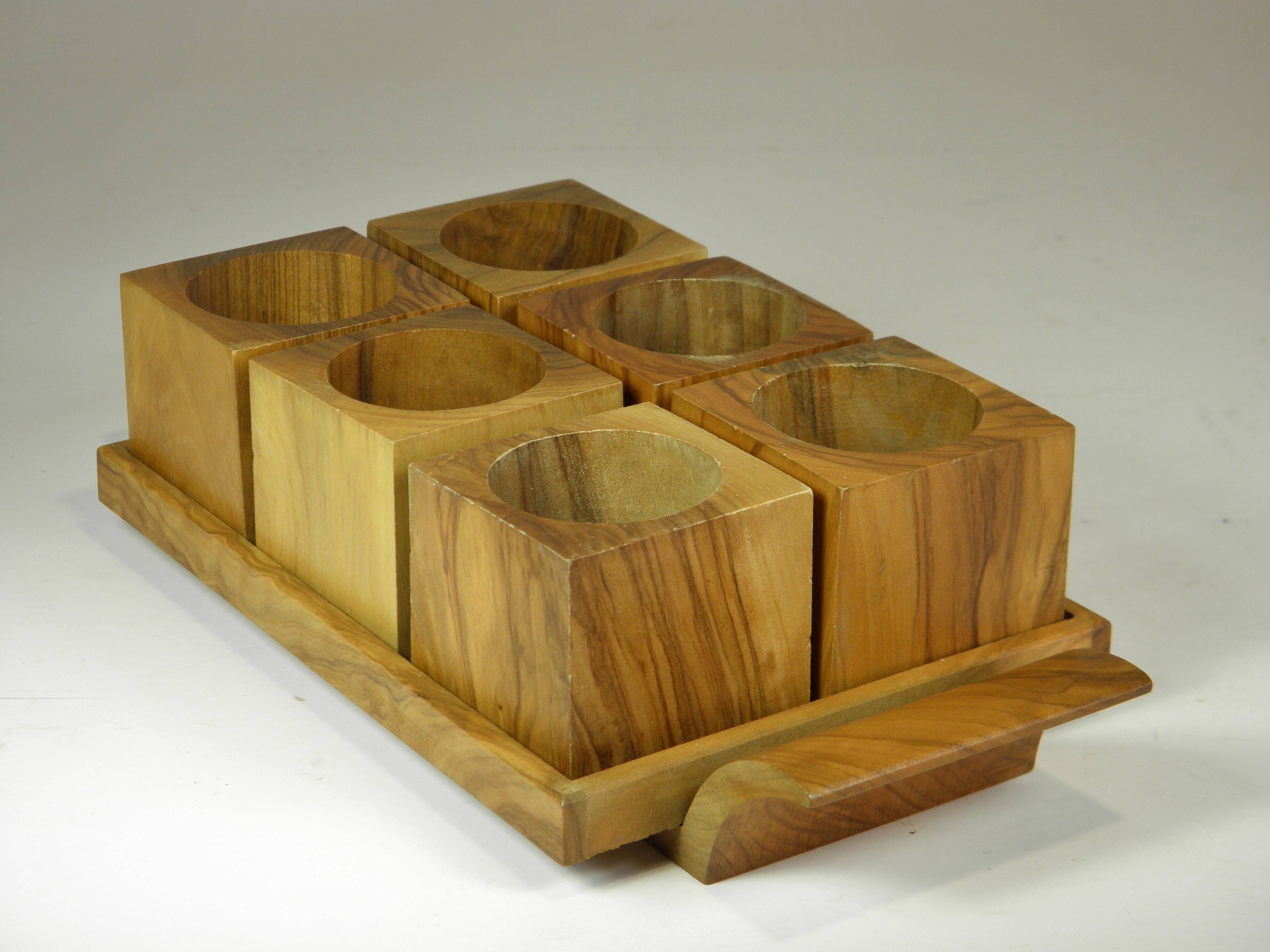 Six egg cups on a wooden tray.