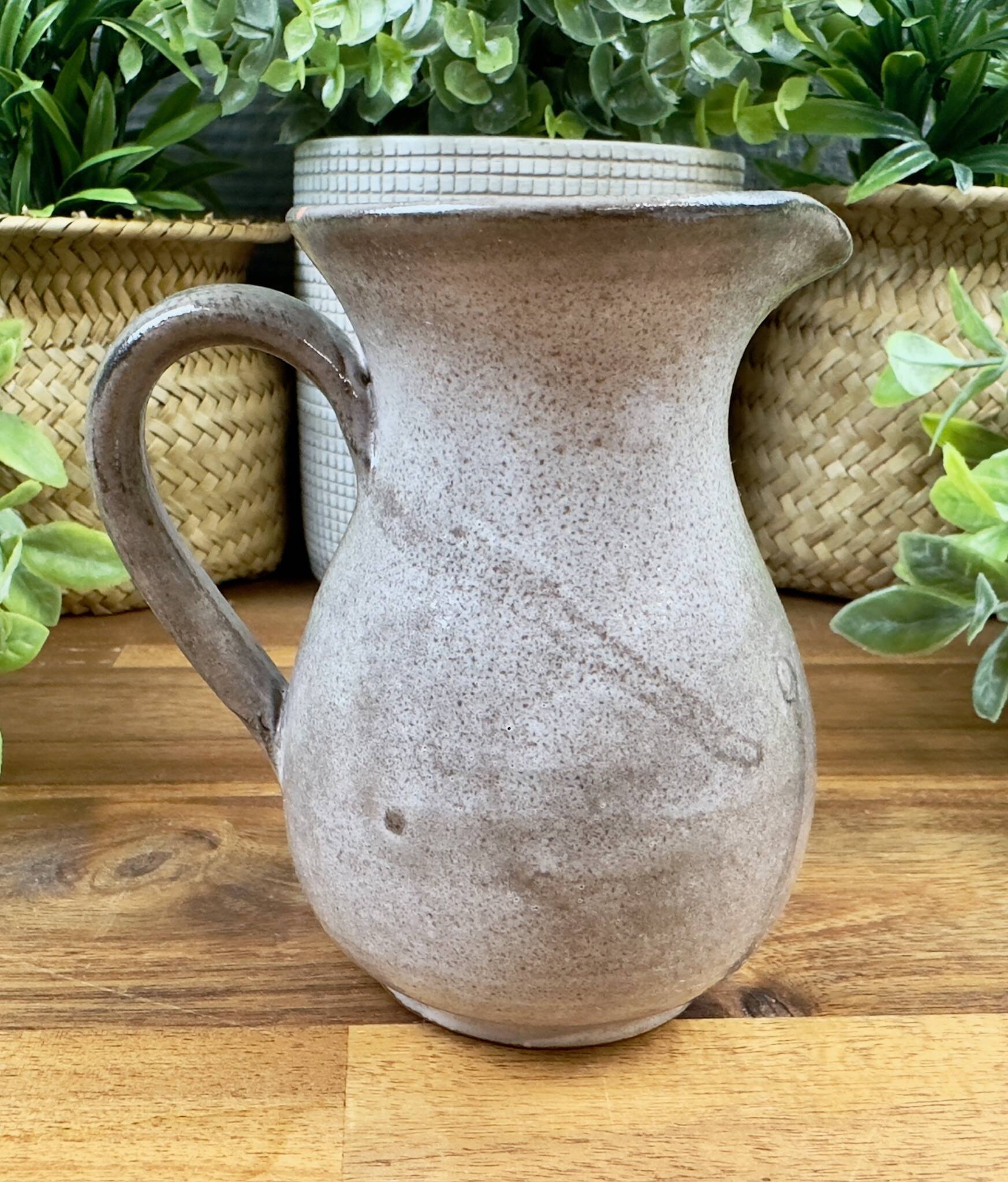 Vintage grey ceramic pitcher with hand-painted blue flower decoration.