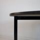 Round dining table in black lacquered metal with a granite top.