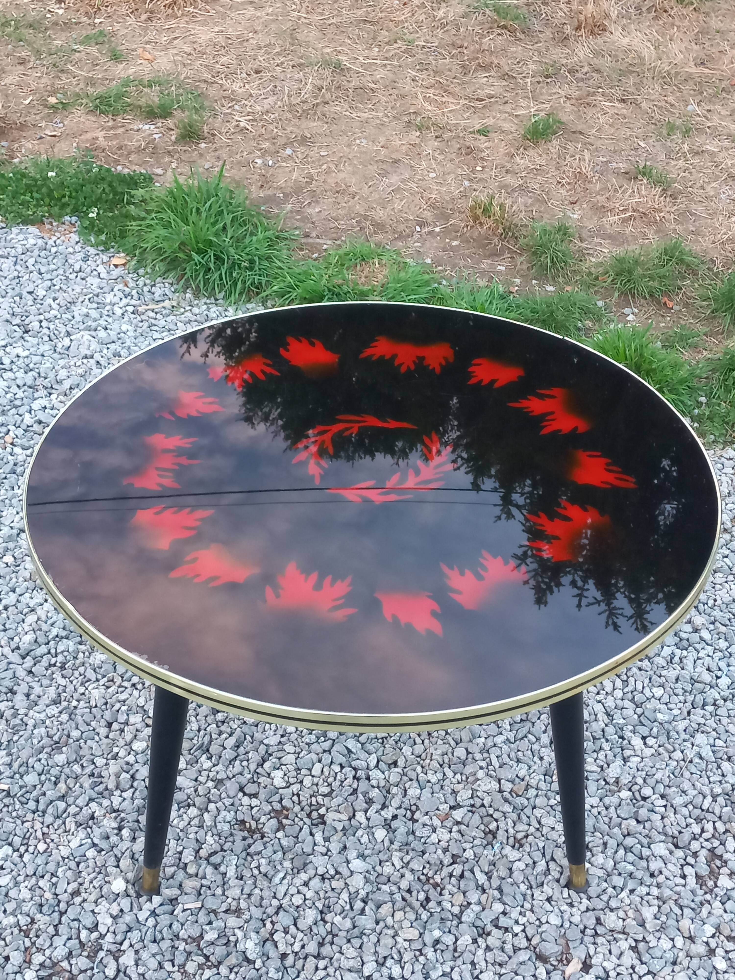 Vintage coffee table with glass top and tripod legs in blackened wood from the 1960s.