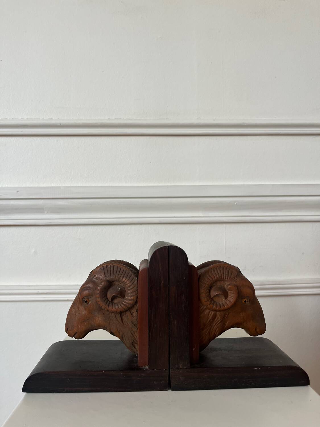 Pair of carved wooden bookends in the shape of ram's heads.