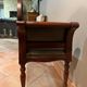 Antique carved wooden bench with green upholstered seat and backrest.