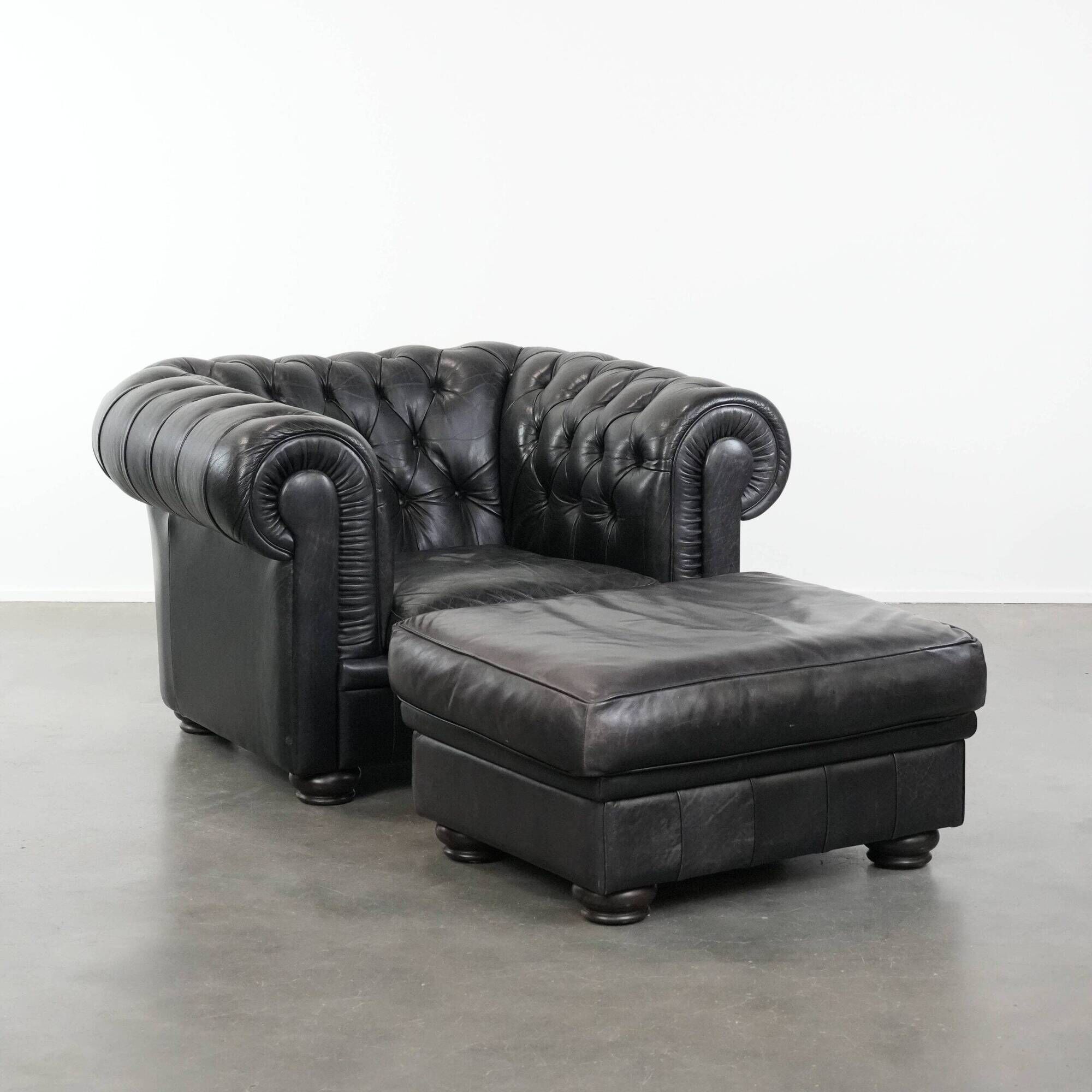 Set of a black cowhide leather Chesterfield armchair and matching ottoman