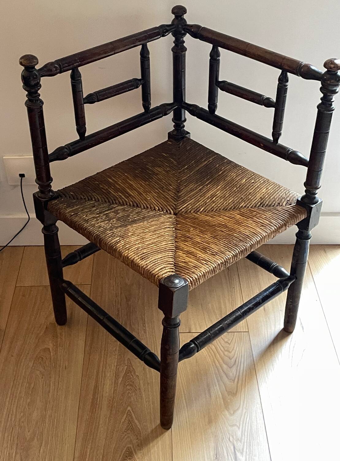 Corner chair made of turned wood with a straw seat.