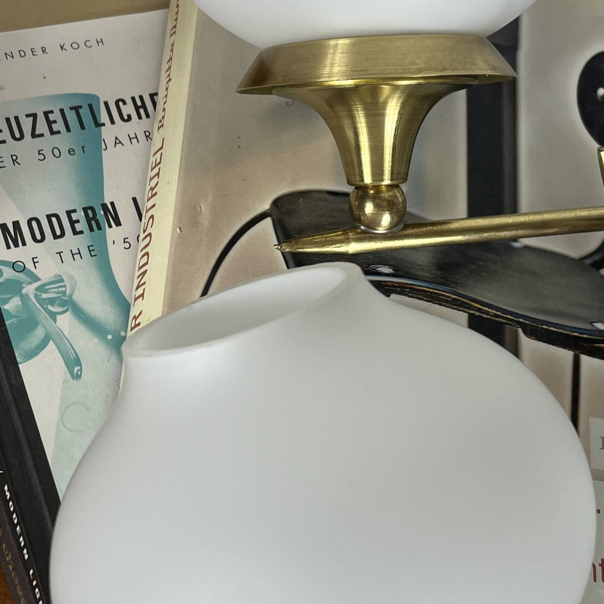 Pair of vintage wall sconces in brass with white glass globe shades.