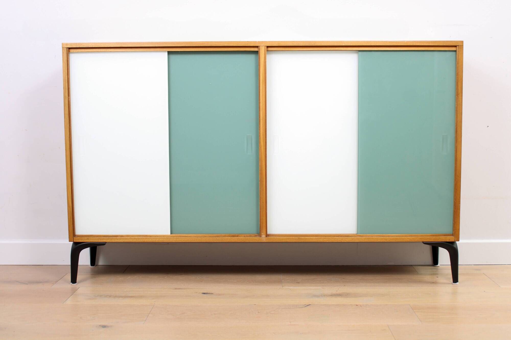 A vintage mid-century bookshelf/sideboard with green and white sliding door