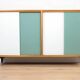 A vintage mid-century bookshelf/sideboard with green and white sliding door