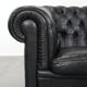 Ensemble composé d'un canapé chesterfield noir, d'un fauteuil et d'un pouf.