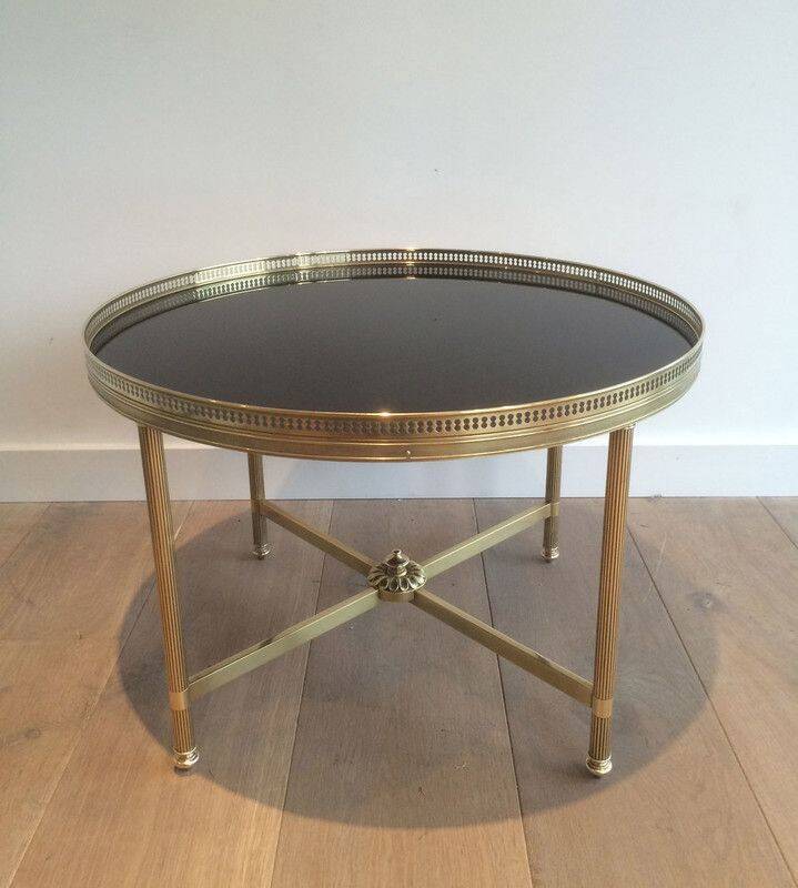 Round coffee table in brass with a black lacquered glass top by Maison Jansen.