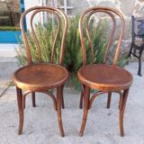 pair of round wooden chairs with a pattern on the seat