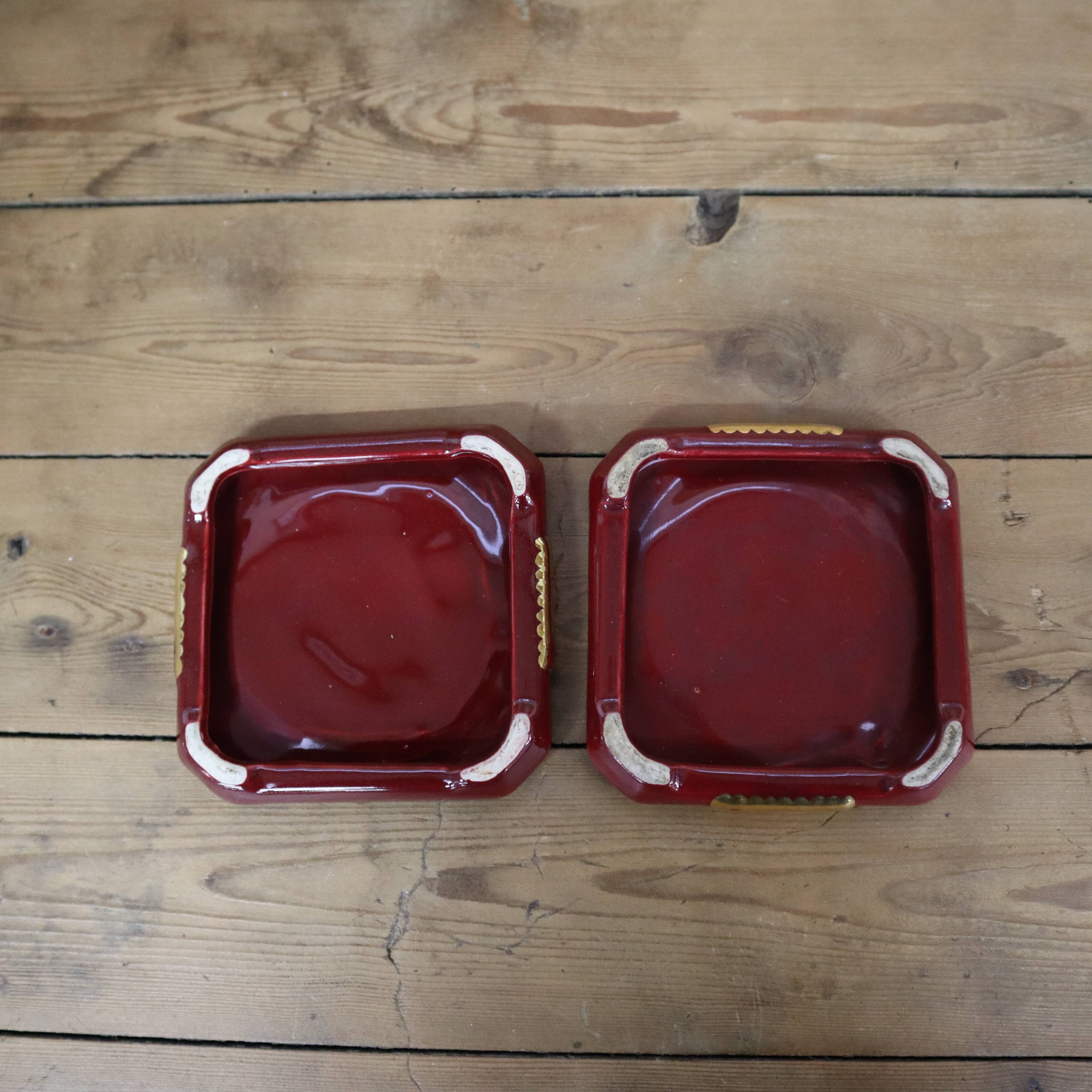 Pair of burgundy ceramic coasters or bottles with gold trim