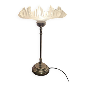 Table lamp with a silver base and a scalloped shade.