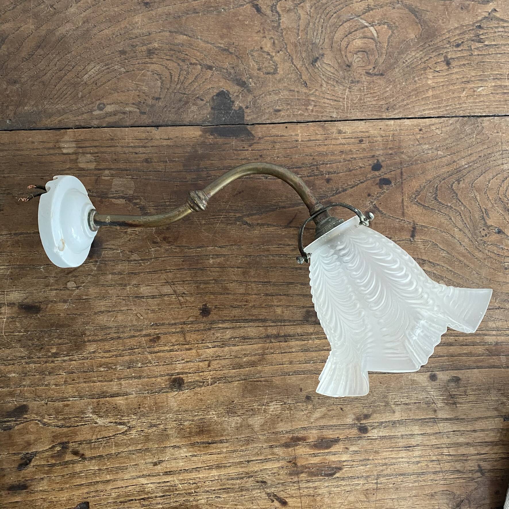 Antique swan neck wall light in brass and porcelain with a glass shade.