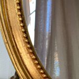 Oval-shaped wooden mirror in gold color