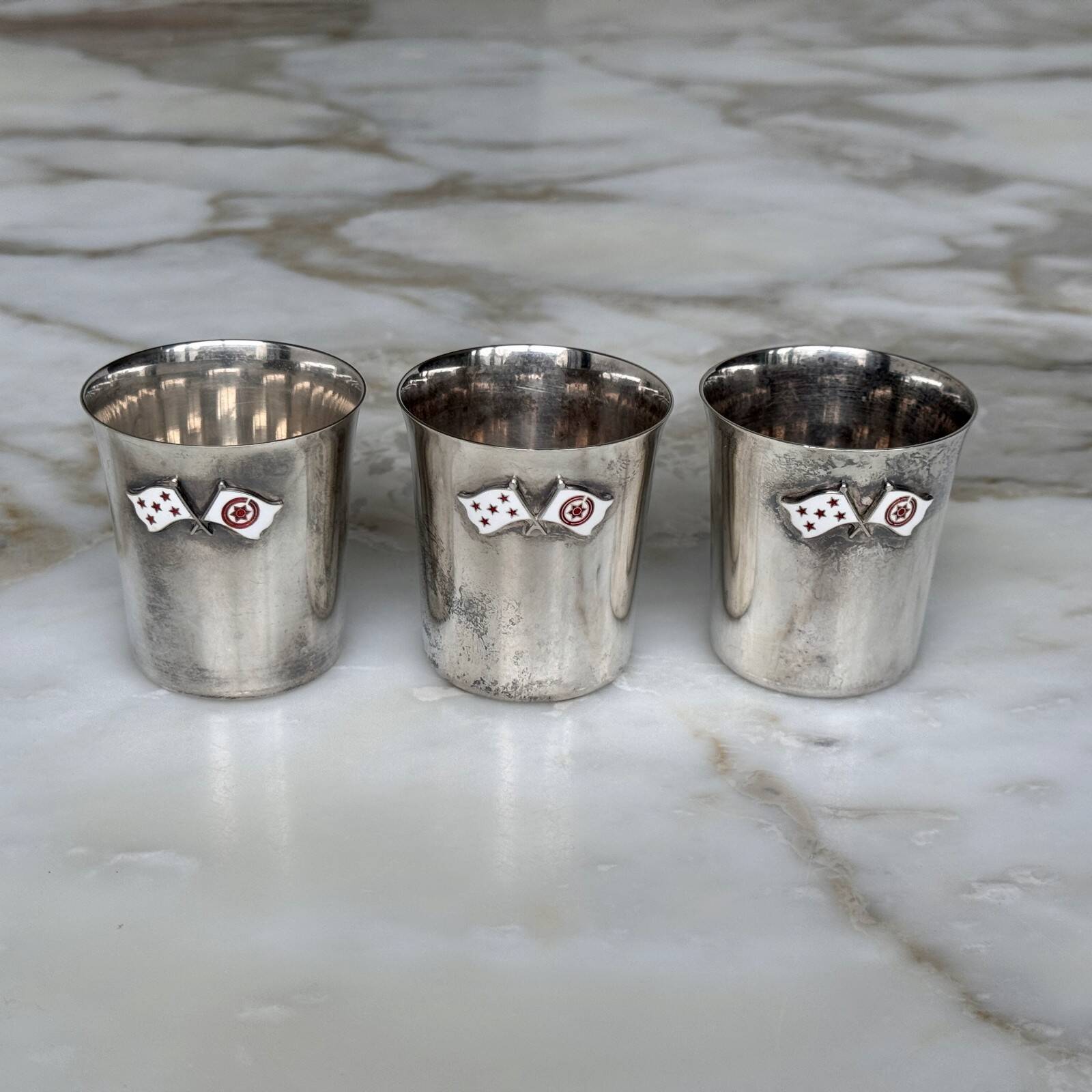 Set of 3 small silver 970 sterling cups with enamelled flags from the 20th century.