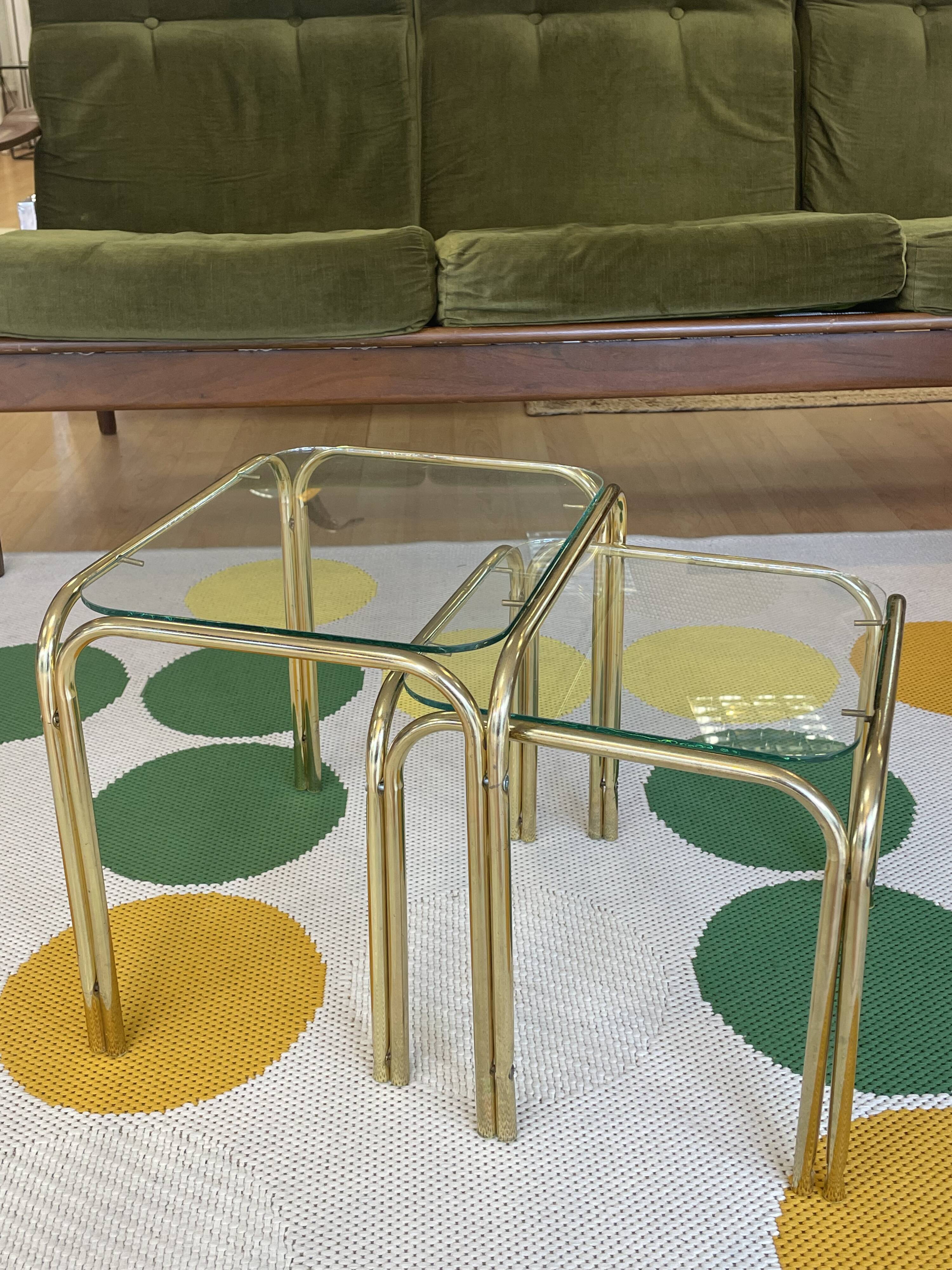 Pair of small nesting coffee tables in gold tubular metal & transparent glass tops