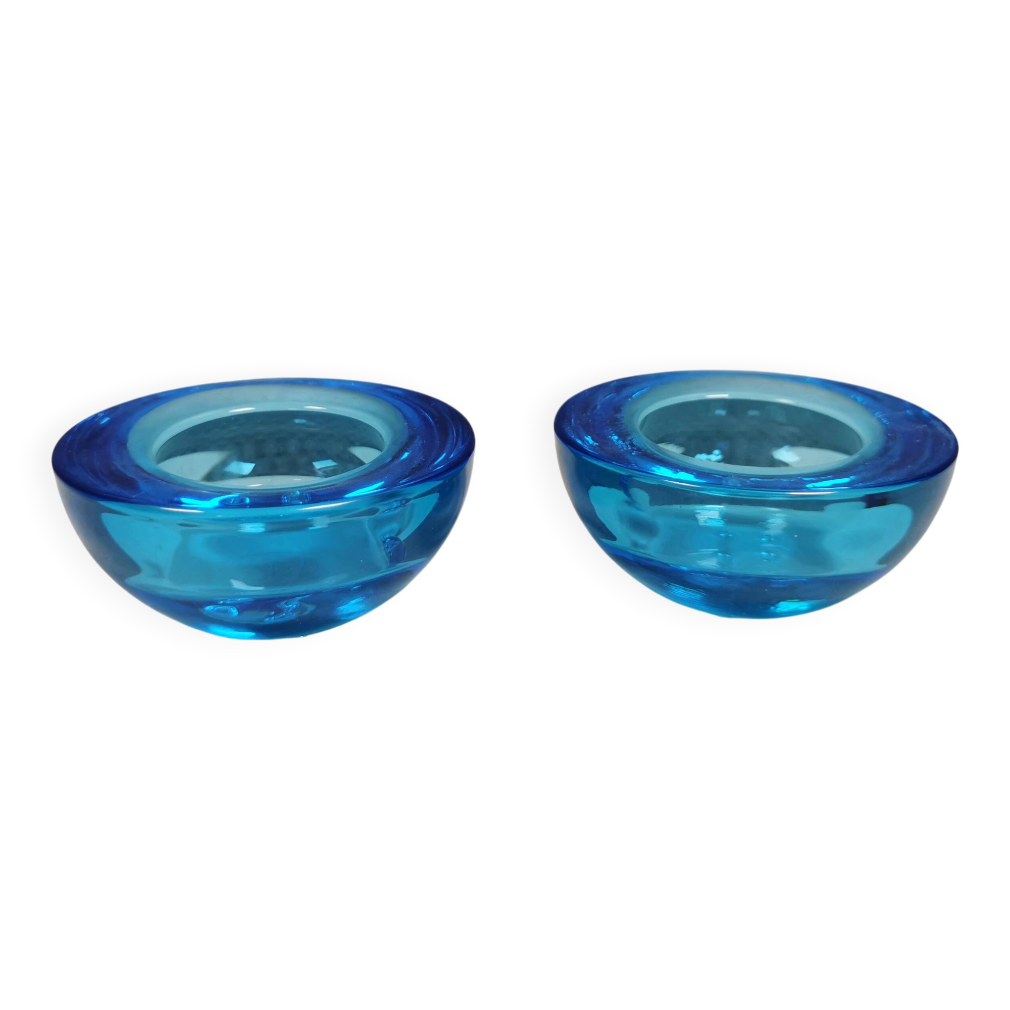 A set of iitalla candle holders in blue transparent glass.