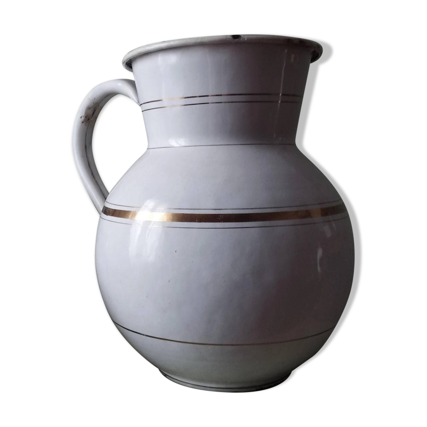 Old enamelled metal jug with gold trim.