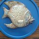 Vallauris ceramic wall sculpture of a relief fish on a blue plaque.