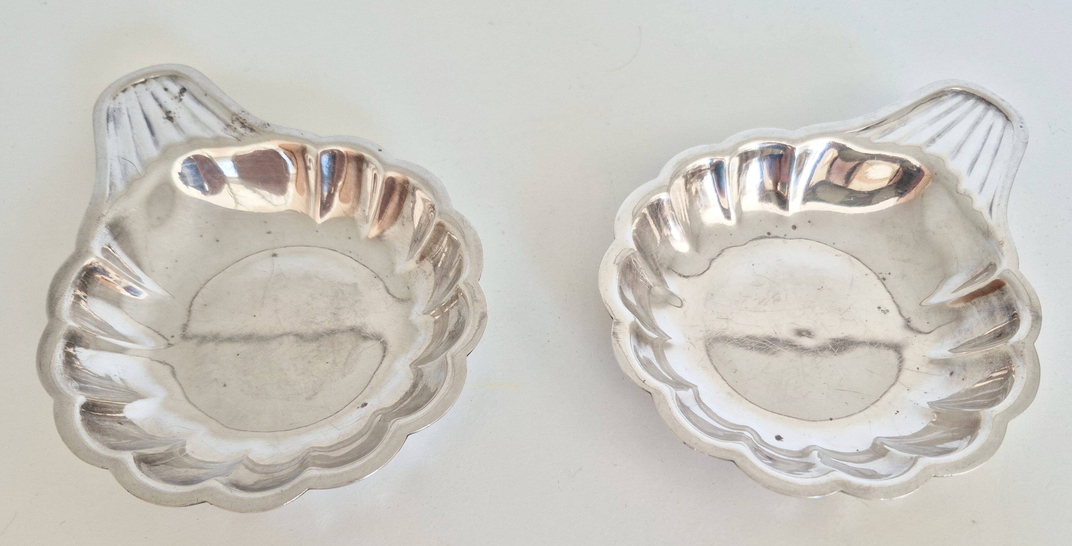 Silver-plated shell-shaped butter dishes, in the shape of a scallop shell.