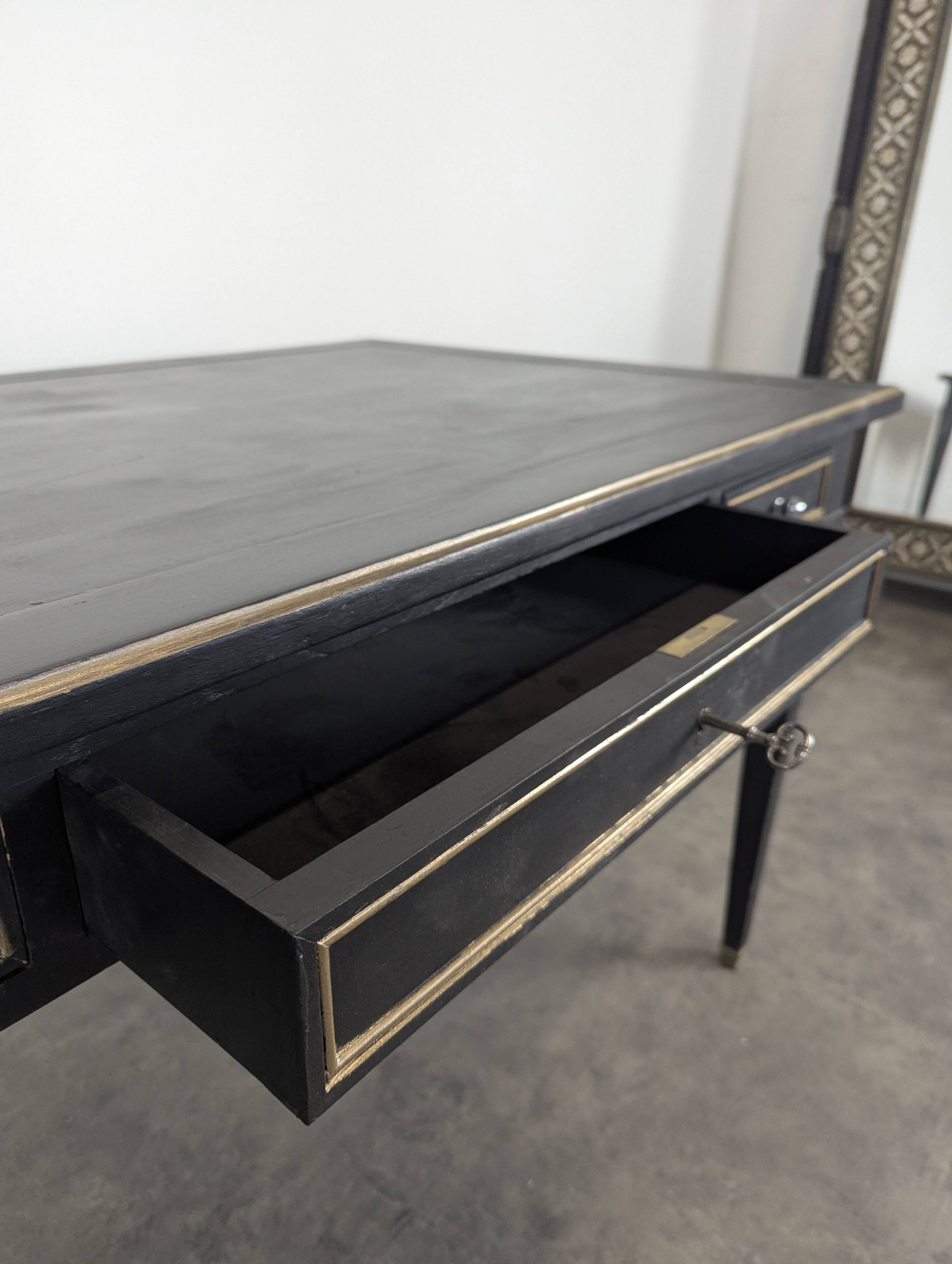 Large flat desk in Louis XVI style, black lacquered with gold highlights.