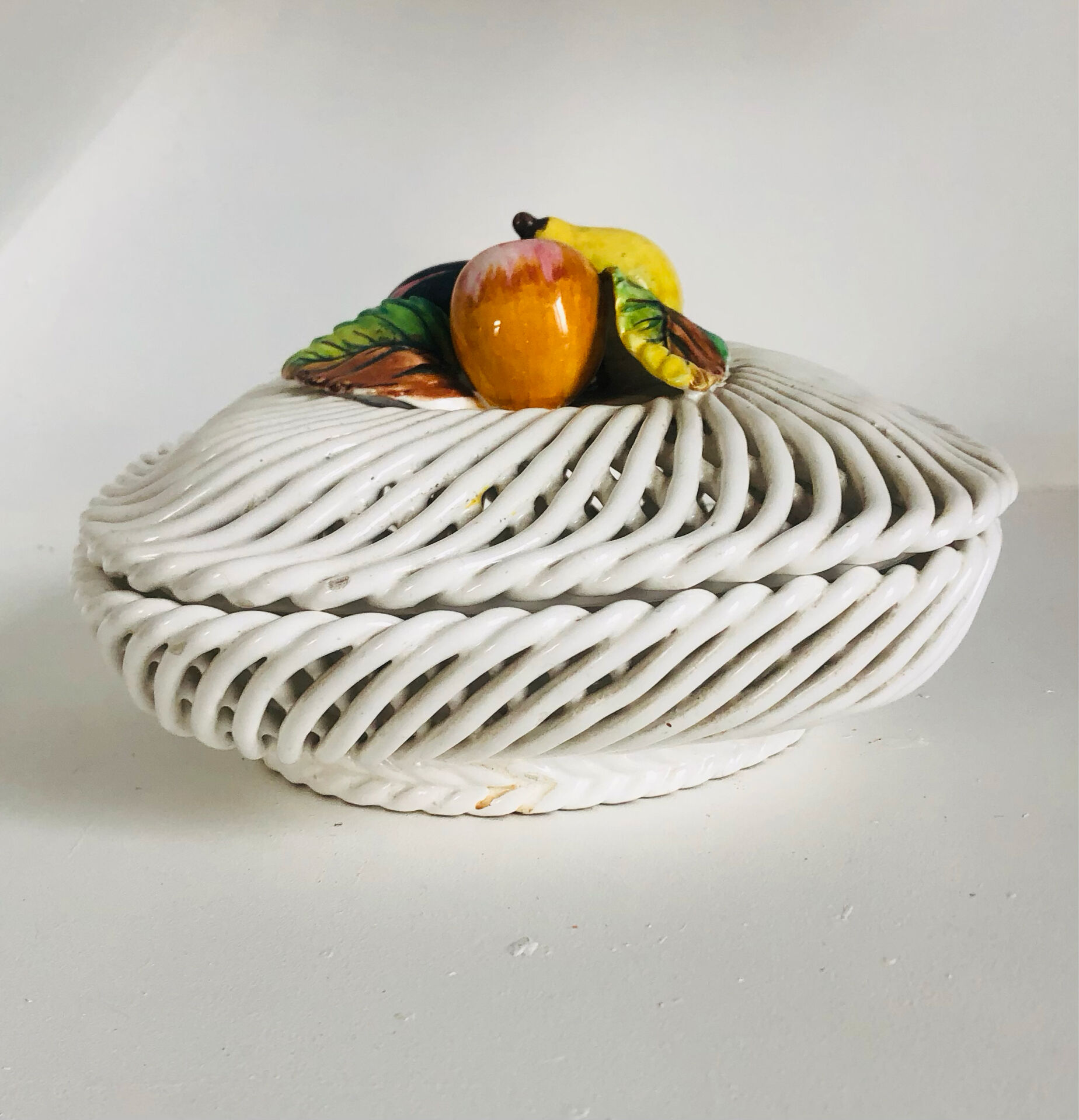 Covered basket in white woven ceramic and fruit slip.